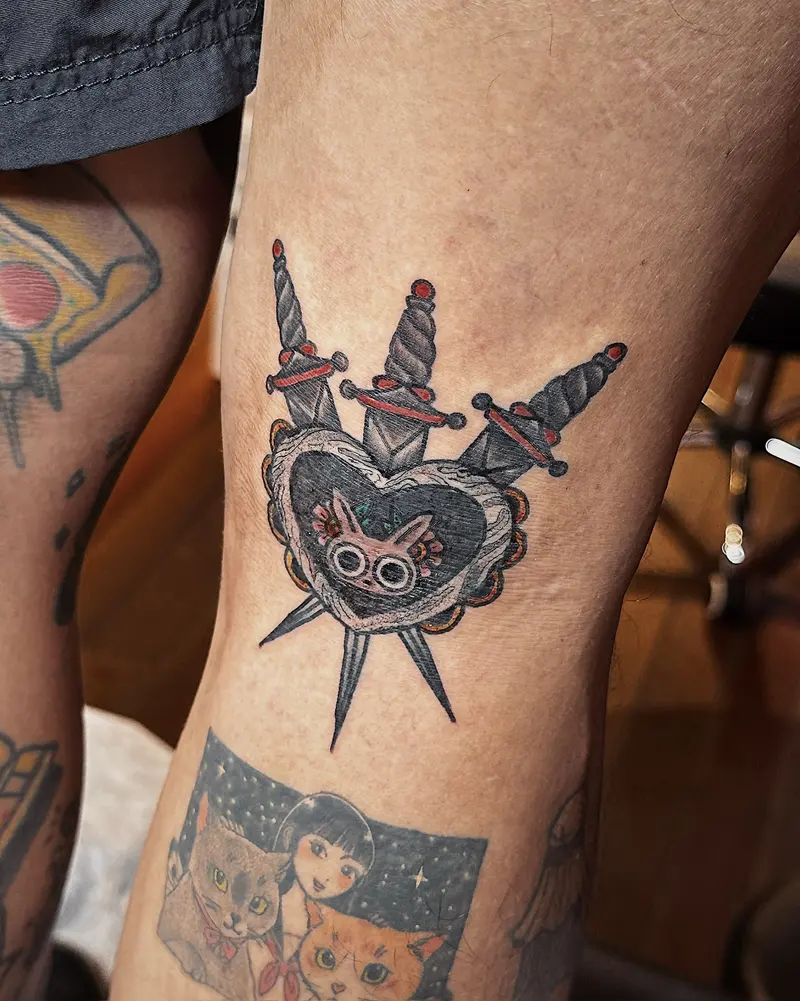 Tattoo work: a traditional heart and crossed daggers in colour, on a thigh