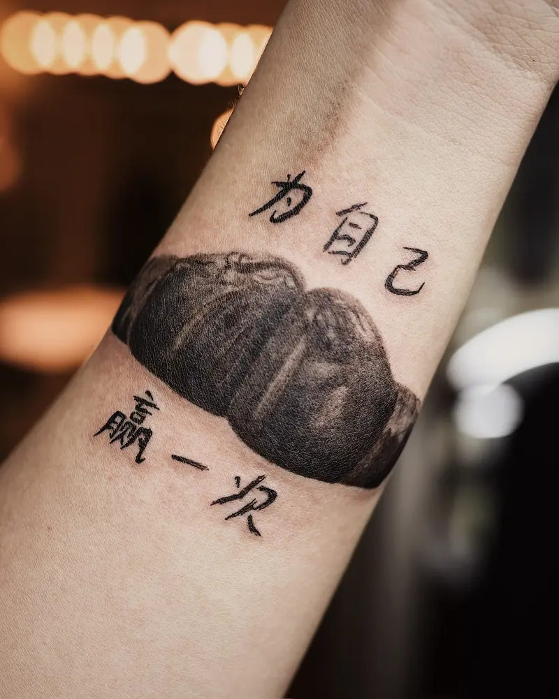 Tattoo work: Chinese lettering above a shaded rock, wrapping a forearm
