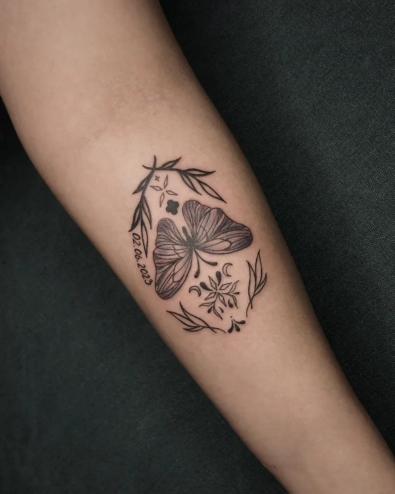 Tattoo work: a butterfly among small florals, on an inner arm