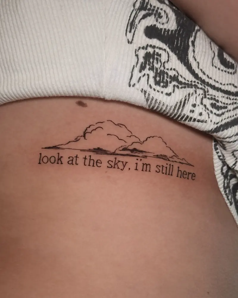 Tattoo work: a horizon line under the words “look at the sky, i’m still here”, on the ribs